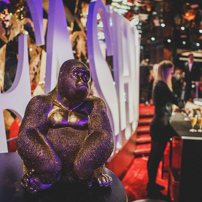 Goldene Gorilla Statue vor Fashion Night Schriftzug und Barfrau