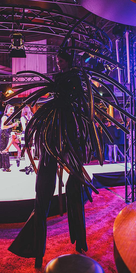 Frau auf Stelzen in Kostüm an der Fashion Night